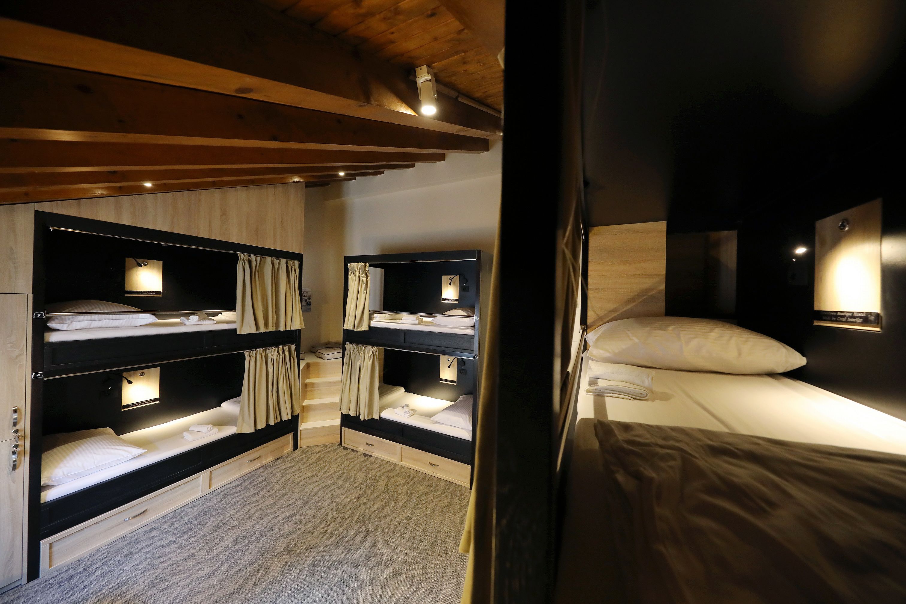 Une chambre avec des lits superposés, des poutres en bois et un petit bureau avec une lampe.