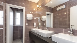 Un baño moderno con dos lavamanos, un espejo y una ducha.