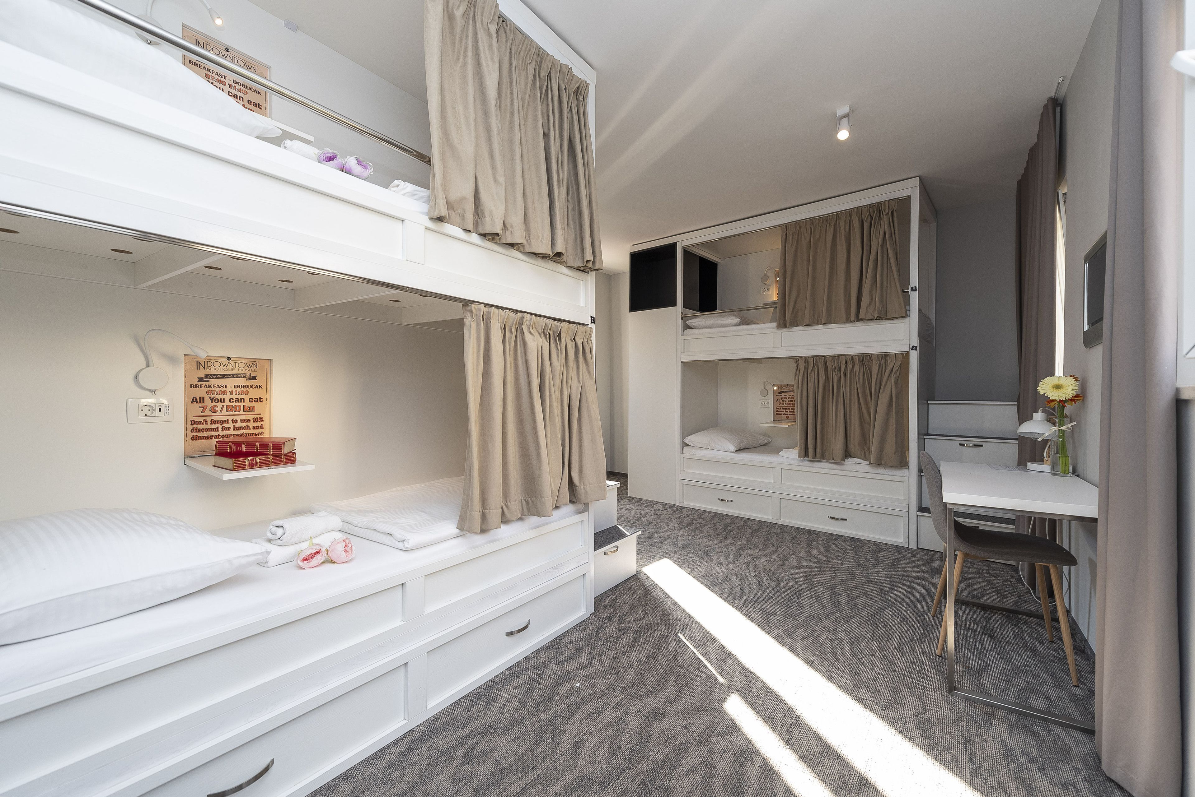 A modern hotel room with bunk beds, a desk, and a small seating area.
