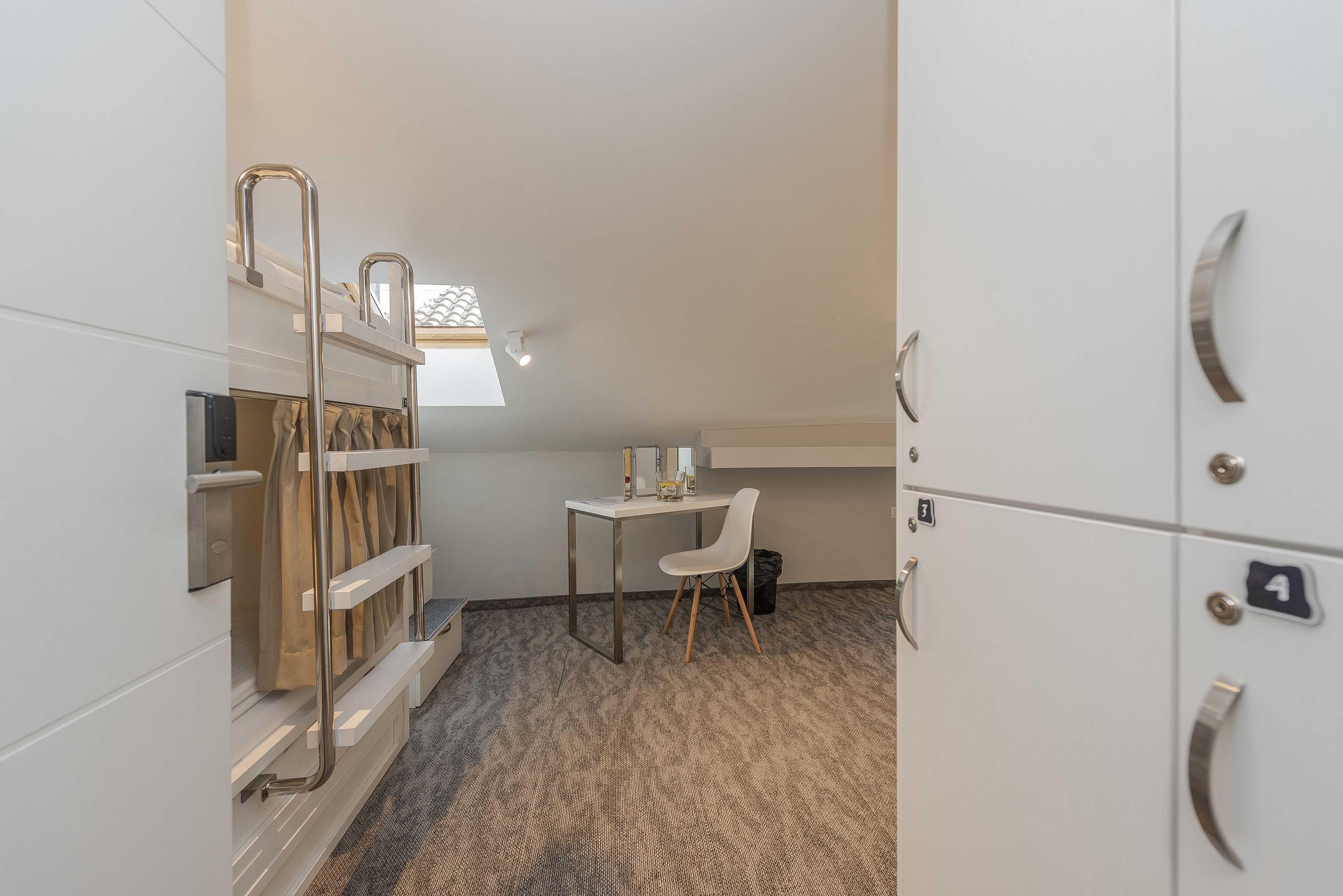 Una stanza compatta con angolo cottura, un piccolo tavolo con una sedia, una luce a soffitto e una finestra vista.