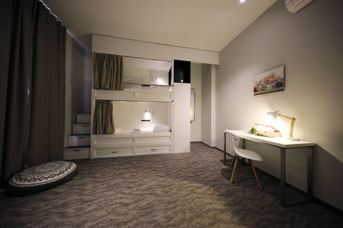 Ein Schlafzimmer mit einem Etagenbett, einem Schreibtisch mit Lampe und einem kleinen runden Teppich.