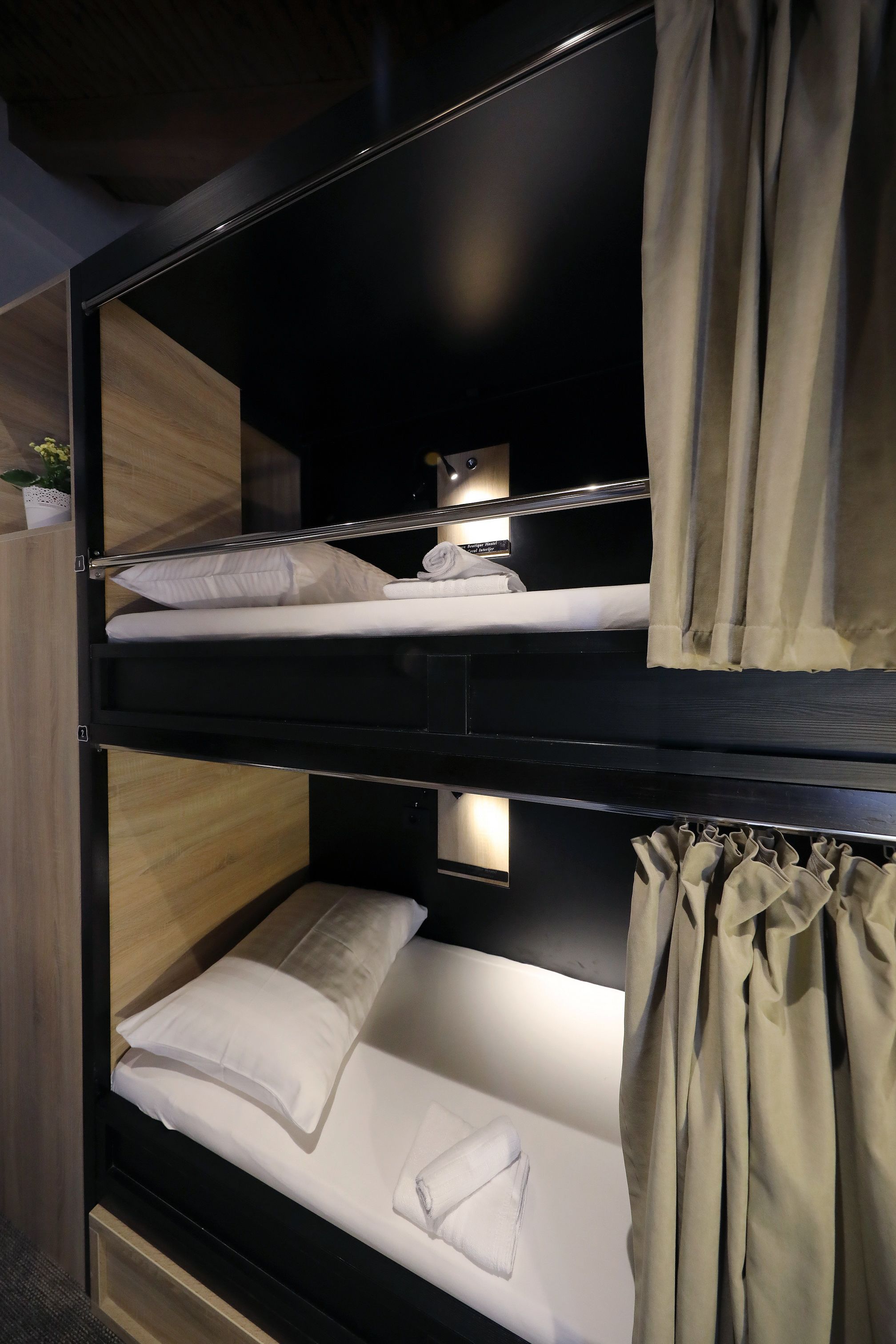 A bunk bed with a wooden headboard, a small bedside table, and a curtain.