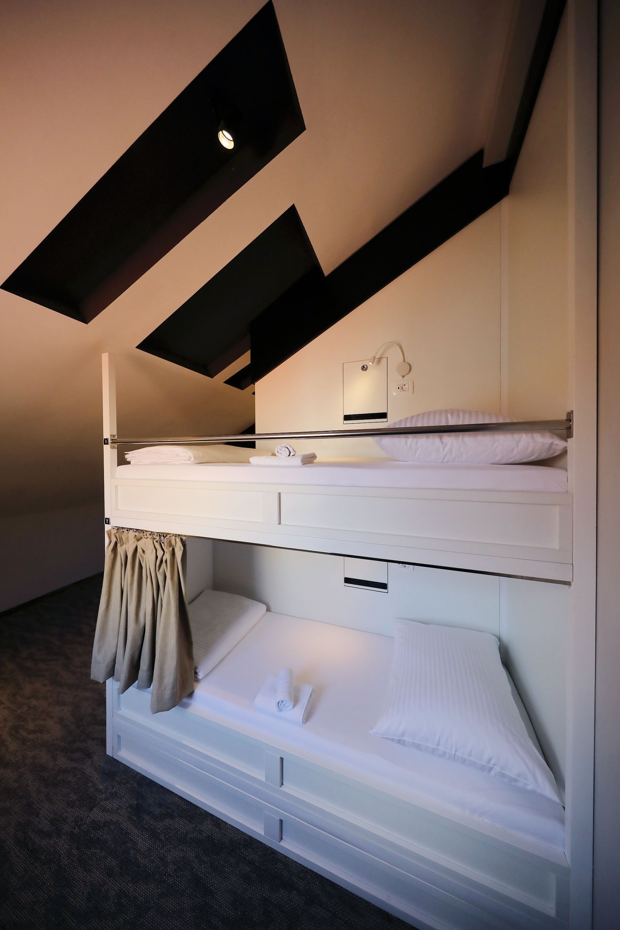 Un lit superposé avec un bureau et une lampe, une fenêtre avec vue et un luminaire au plafond.