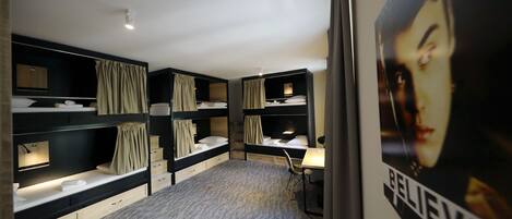 Une chambre avec des lits superposés, un bureau et une affiche.