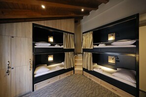 Ein Zimmer mit zwei Etagenbetten, einem Holzschrank und einem kleinen Schreibtisch mit Lampe.