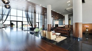 Eine geräumige Lobby mit einer langen Rezeption, einer gemütlichen Sitzecke, großen Fenstern und moderner Ausstattung.