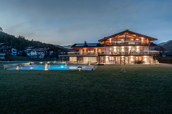 A large, multi-story house with a swimming pool in the foreground.