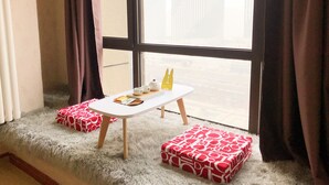 A cozy room with a window, a small white table, and two red patterned cushions on a fluffy rug. - Xi'an Phoenix Holiday Hotel (Xi'an)
