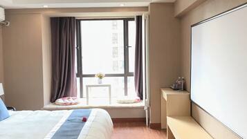 Habitación de hotel con una cama grande, un escritorio, una ventana con cortinas y un televisor de pantalla plana.