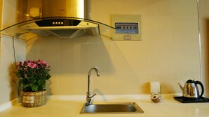 A kitchen with a stainless steel sink, a kettle, a small potted plant, and a wall-mounted control panel. - Xi'an Phoenix Holiday Hotel (Xi'an)