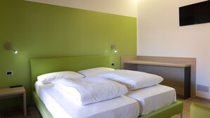 A room with a green bed, a bedside table, a nightstand, a desk, and a wall-mounted TV. - Agritur I Colori (Sanzeno)