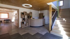 A spacious living area with a wooden ceiling, a built-in kitchen, and a staircase. - Agritur I Colori (Sanzeno)