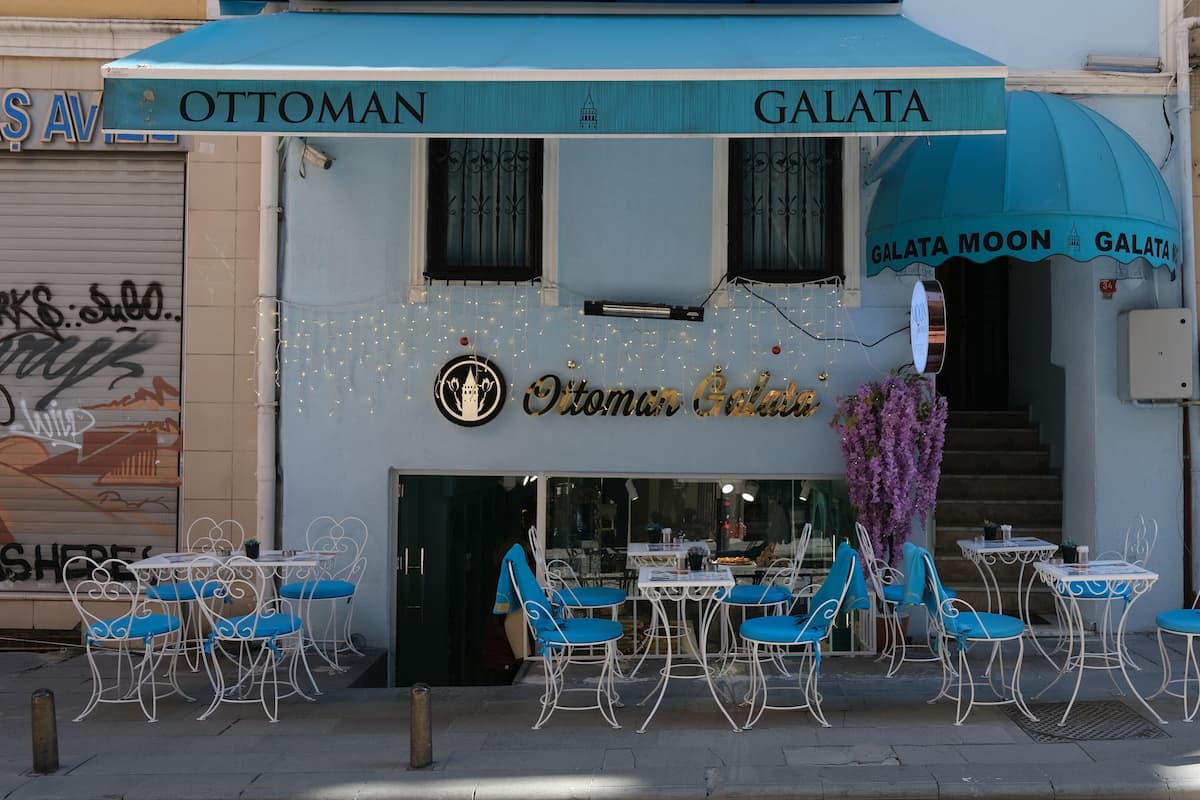 Restaurante chamado "Ottoman Galata" com mesas ao ar livre e uma escadaria que leva à entrada.