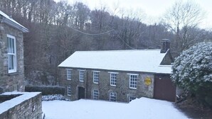 A stone building with a snow-covered roof and a small garden area. - Rock Mill (Llandysul)