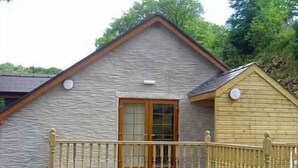 A small stone building with a wooden balcony and a wooden fence. - Rock Mill (Llandysul)