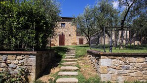 A stone pathway leading to a rustic stone building with a wooden door and windows. - Borgo tra gli Olivi (Castiglion Fiorentino)