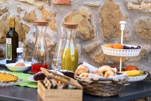 A table set with various food items, including bread, pastries, and a fruit basket. - Borgo tra gli Olivi (Castiglion Fiorentino)