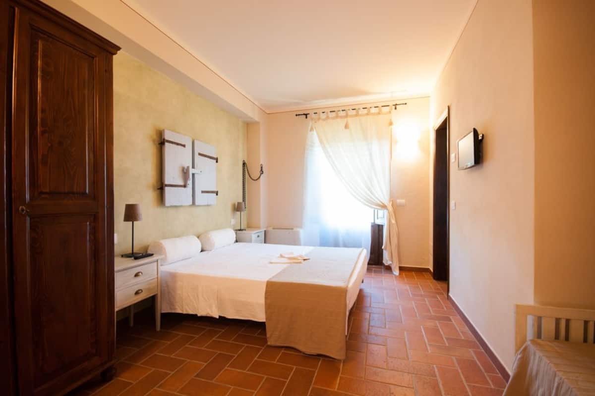 A bedroom with a large bed, a wardrobe, a bedside table, and a nightstand.