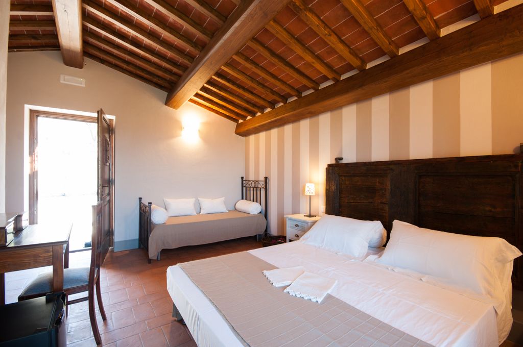 Una camera da letto con due letti, un soffitto in legno, un comodino con una lampada e una finestra.