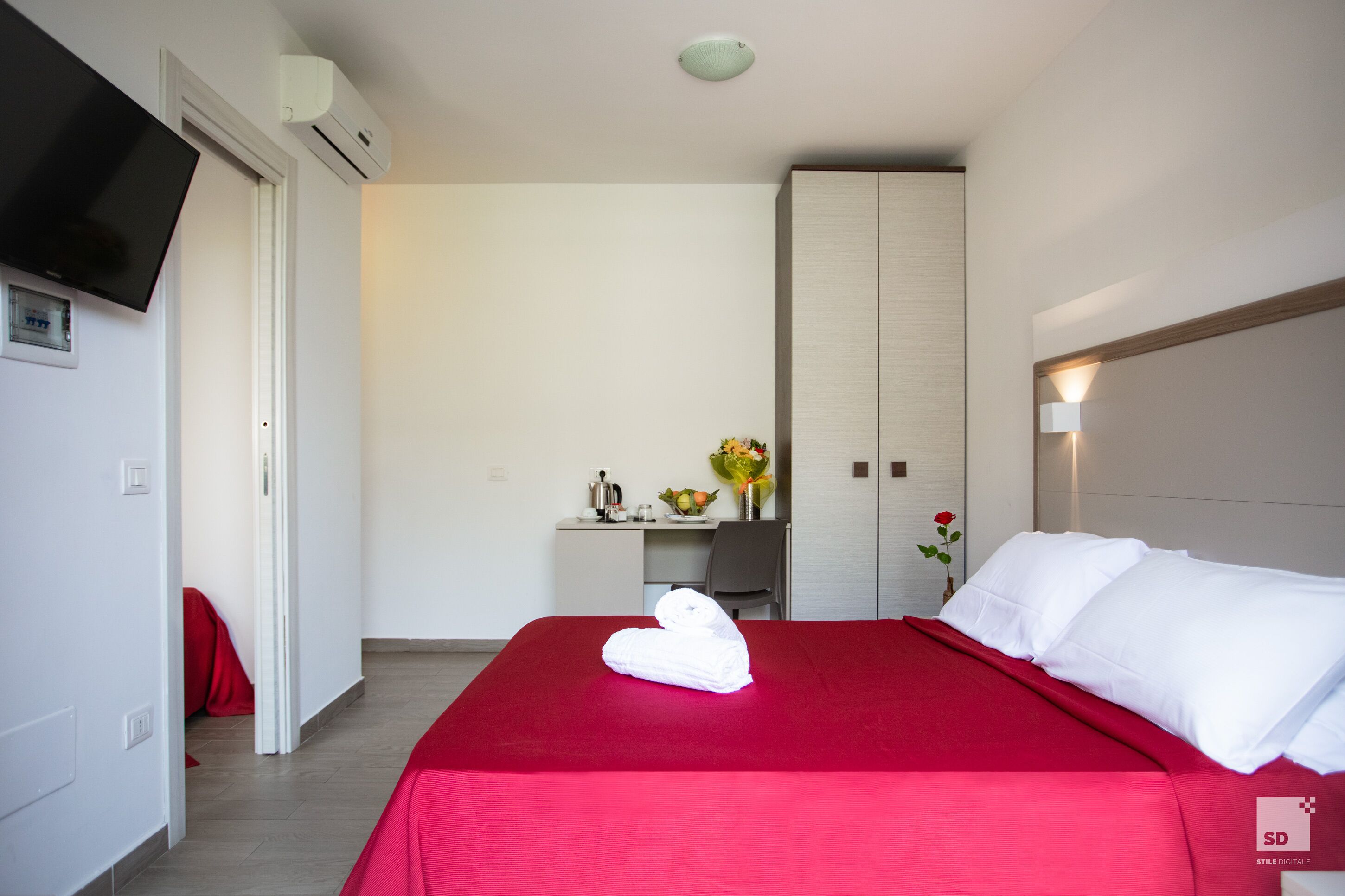 A hotel room with a bed, a desk, a TV, and a wardrobe.