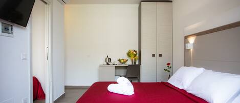 A hotel room with a bed, a desk, a TV, and a wardrobe.