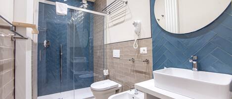 A modern bathroom with a glass shower enclosure, a toilet, a bidet, and a sink with a mirror.