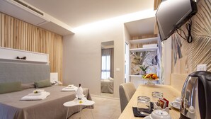 Une chambre d’hôtel comprenant un lit, une table de chevet et un coin repas avec une table, des chaises et une bouilloire.