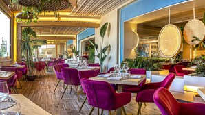 Un restaurant où les tables sont dressées pour le service, avec un assortiment de chaises rouges et violettes.