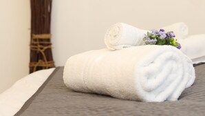 Un espace spa aménagé avec soin, comprenant une serviette blanche pliée, un vase avec des fleurs violettes et une œuvre d’art abstraite accrochée au mur.