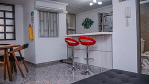 A modern kitchen with a bar area, a dining table with chairs, and a black sofa. - Park Lleras 301 (Medellín)