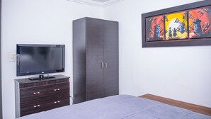 A bedroom with a bed, a TV on a dresser, a wardrobe, and a framed picture on the wall. - Park Lleras 301 (Medellín)