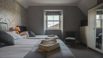 A bedroom with two beds, a window with a view, a dresser, and a chair.