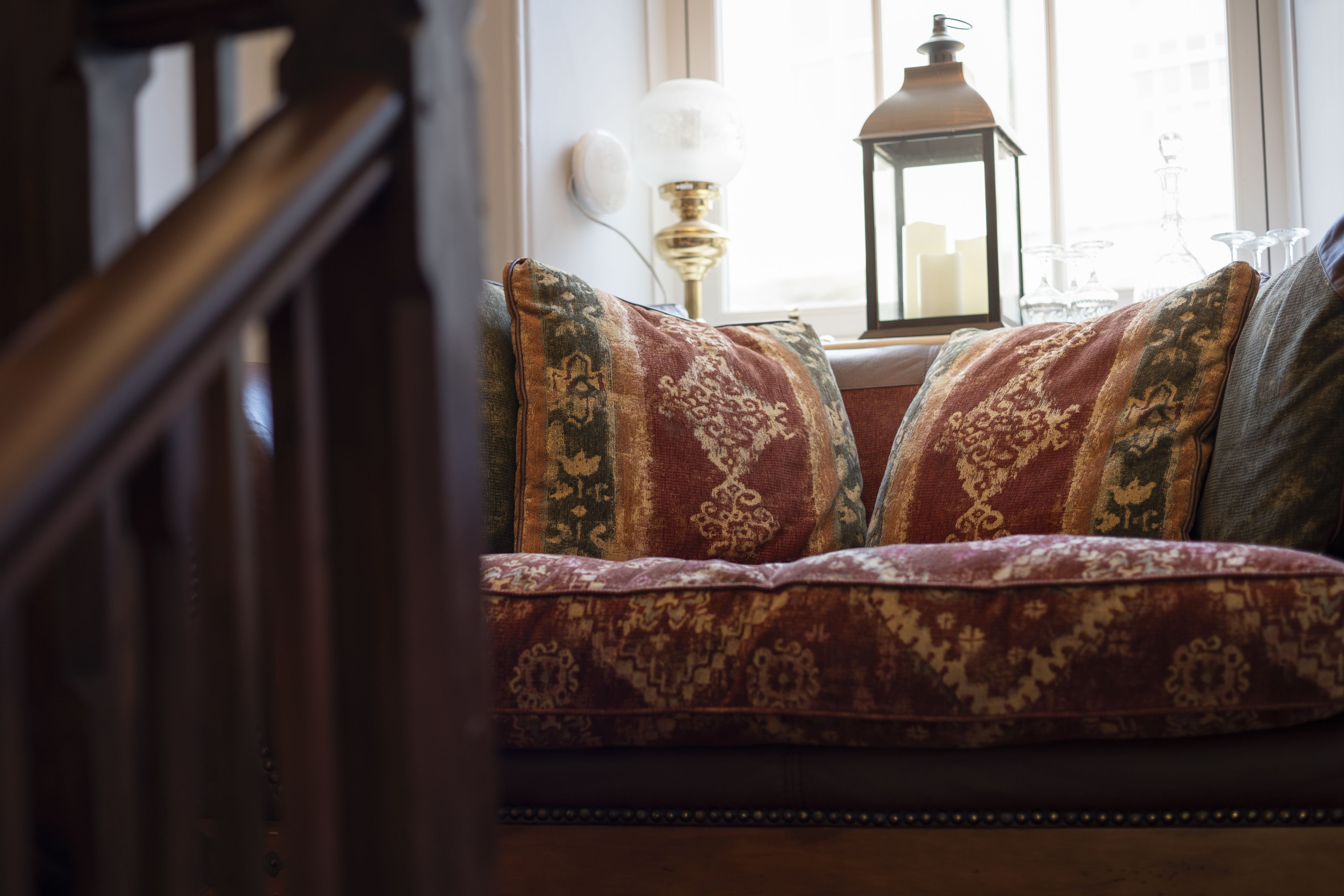 A cozy seating area with patterned cushions, a decorative lamp, and a window with a view.