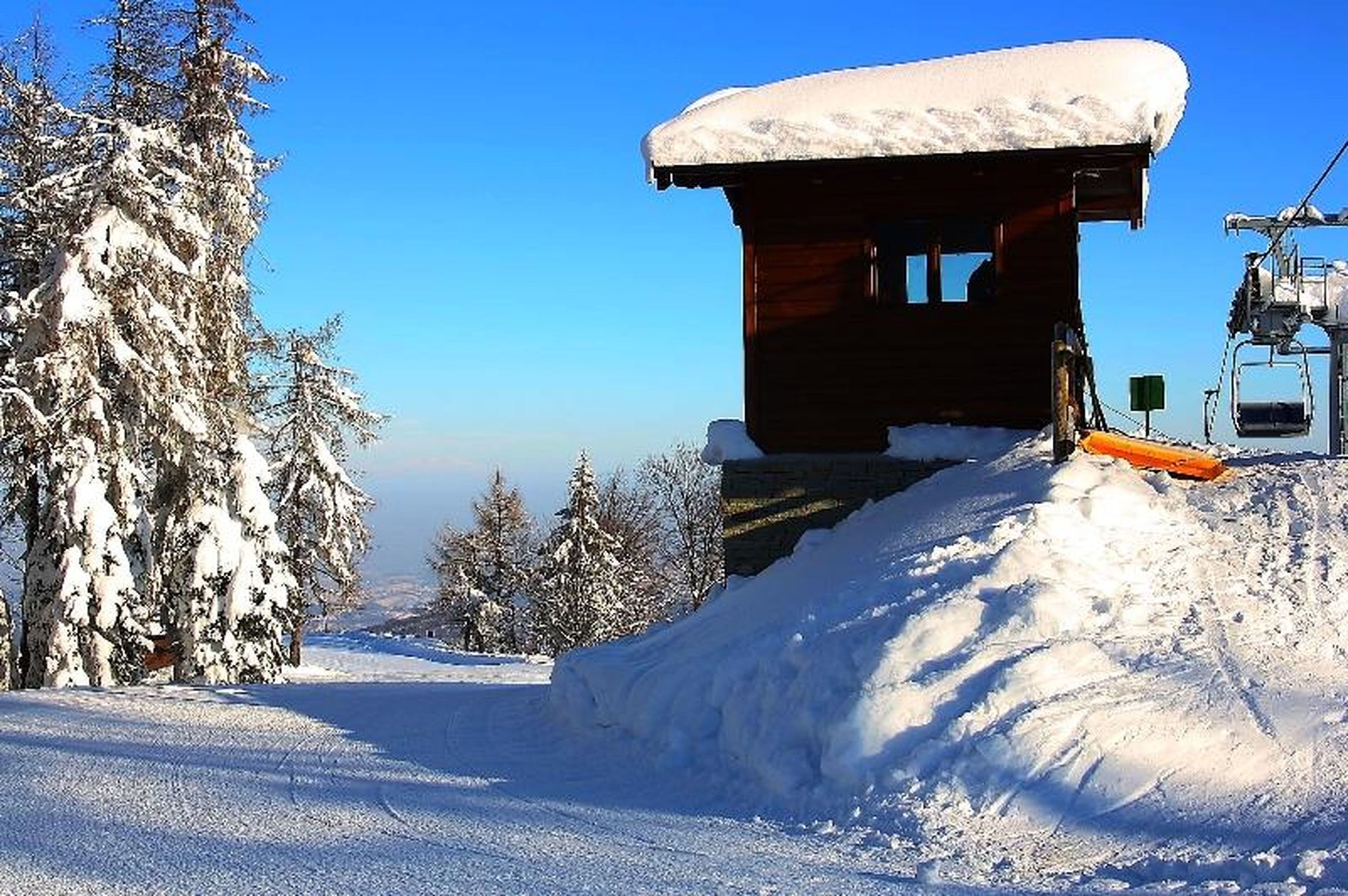 A snow-covered mountain lodge with a ski lift, surrounded by snow-laden trees.