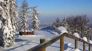 Schneebedeckte Landschaft mit Holzzaun und einem abgelegenen Häuschen.