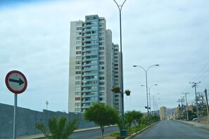 A tall residential building with a clear road in front. - Depto Huayquique Iquique 1153 (Iquique)