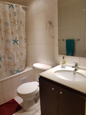 A bathroom with a toilet, a sink, a mirror, and a shower curtain with a starfish pattern. - Depto Huayquique Iquique 1153 (Iquique)