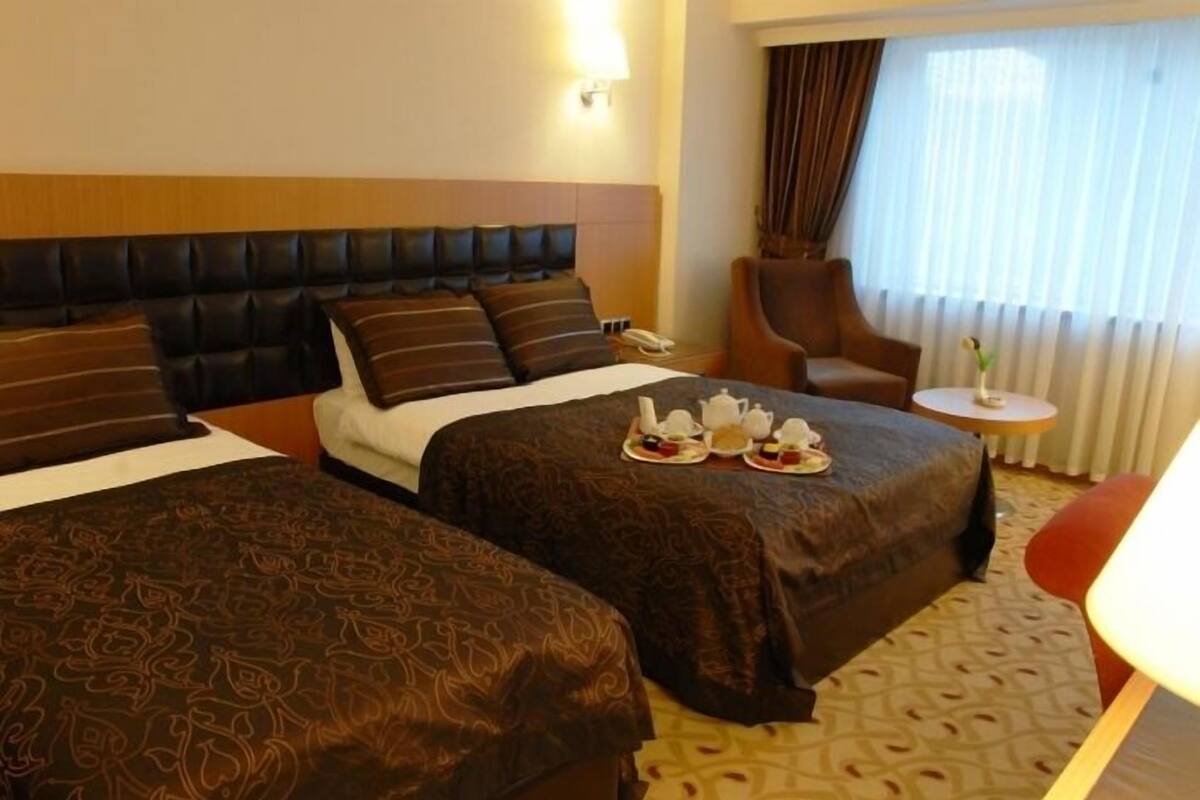 A hotel room with two beds, a sitting area, and a small table with a lamp.