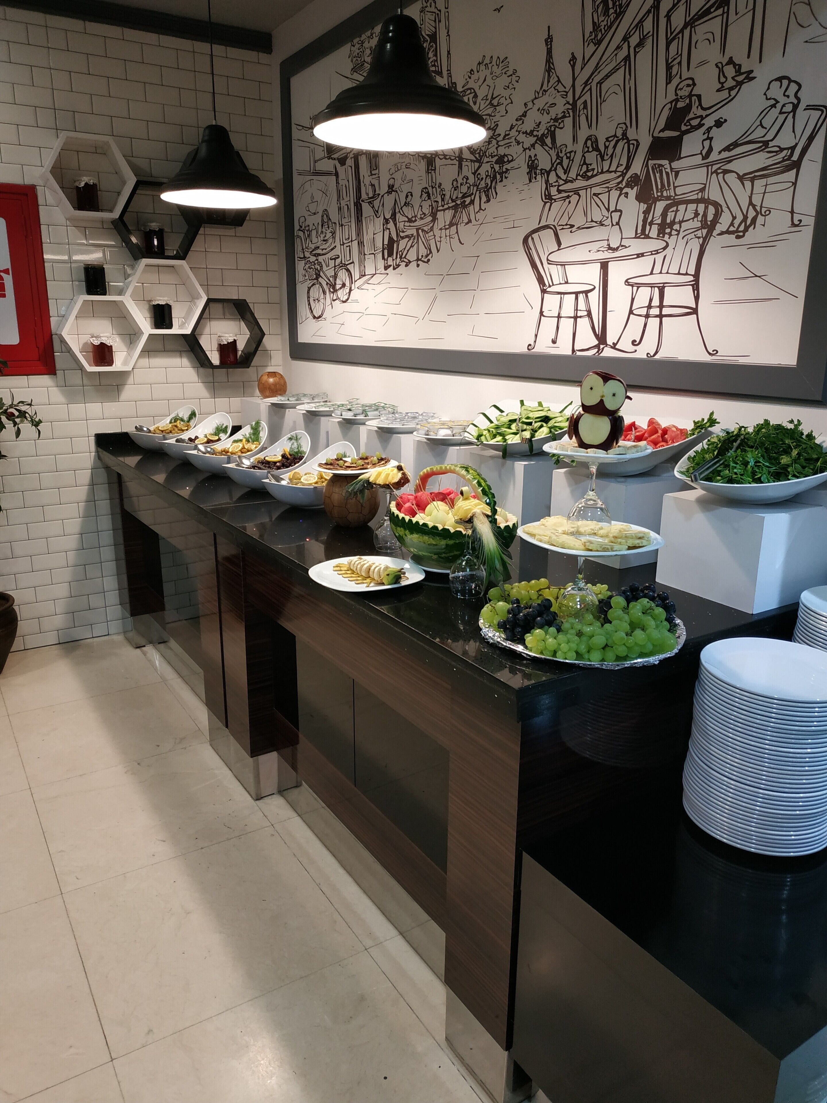 A buffet setup with various food items and a mural on the wall.