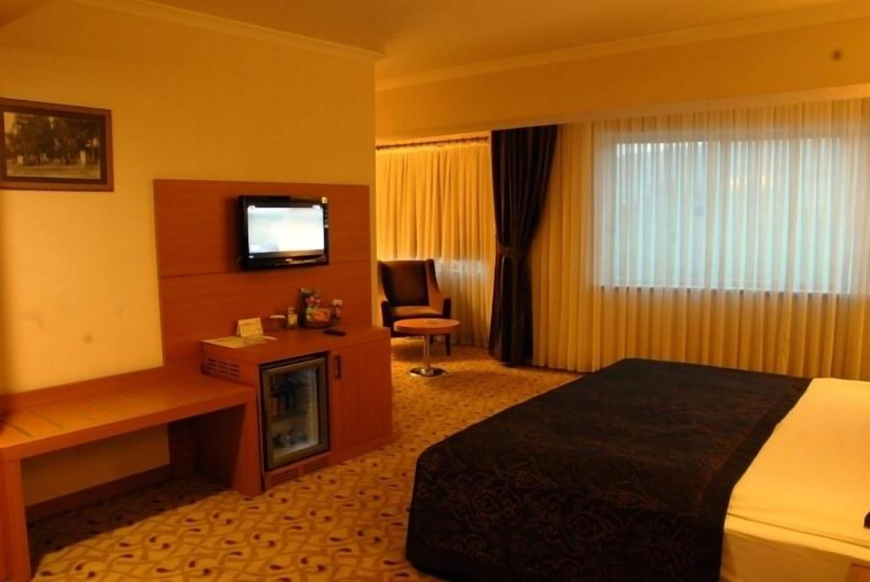 Une chambre d’hôtel comprenant un lit, un bureau avec une télévision, une chaise et une petite table.