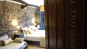A bedroom with a stone wall, a bed with white bedding, and a nightstand with a lamp. - Posada La Corralada (Liérganes)