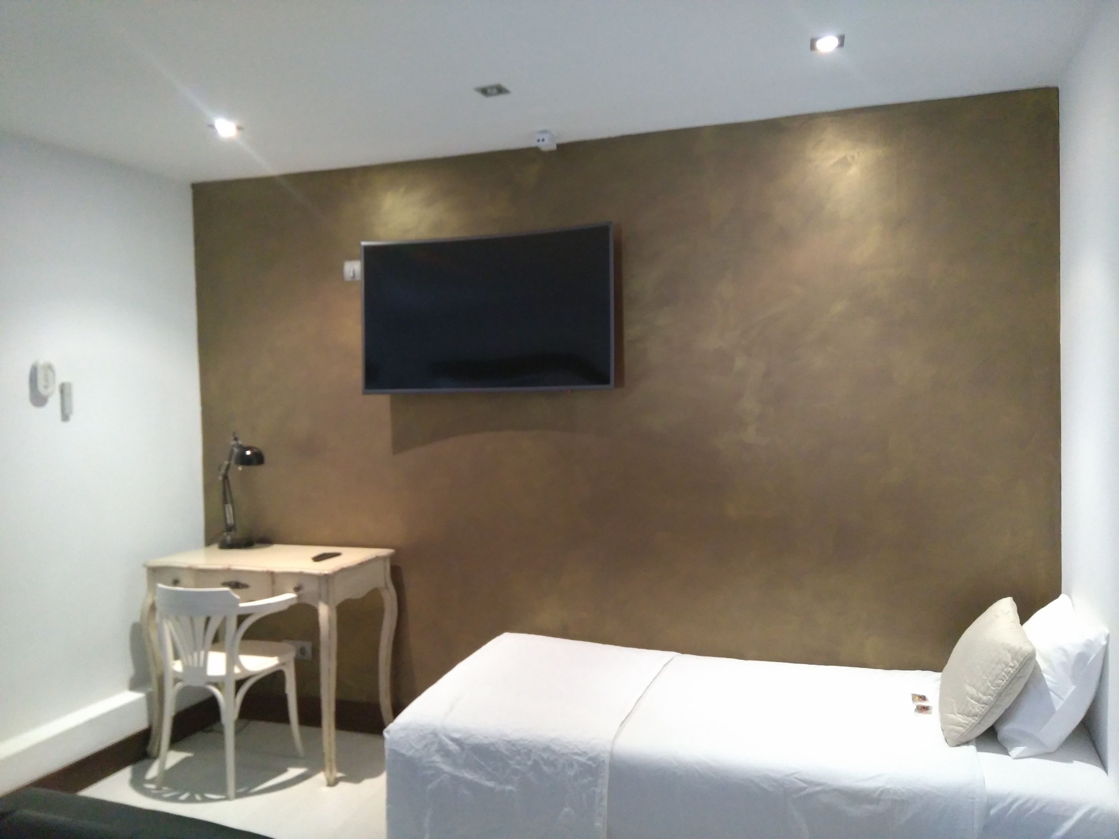 A modern hotel room with a bed, a desk, and a chair.