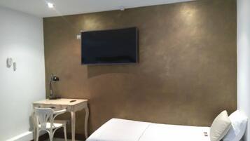 A modern hotel room with a bed, a desk, and a chair.