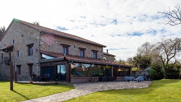 A stone building with a patio area and outdoor seating. - Posada La Corralada (Liérganes)