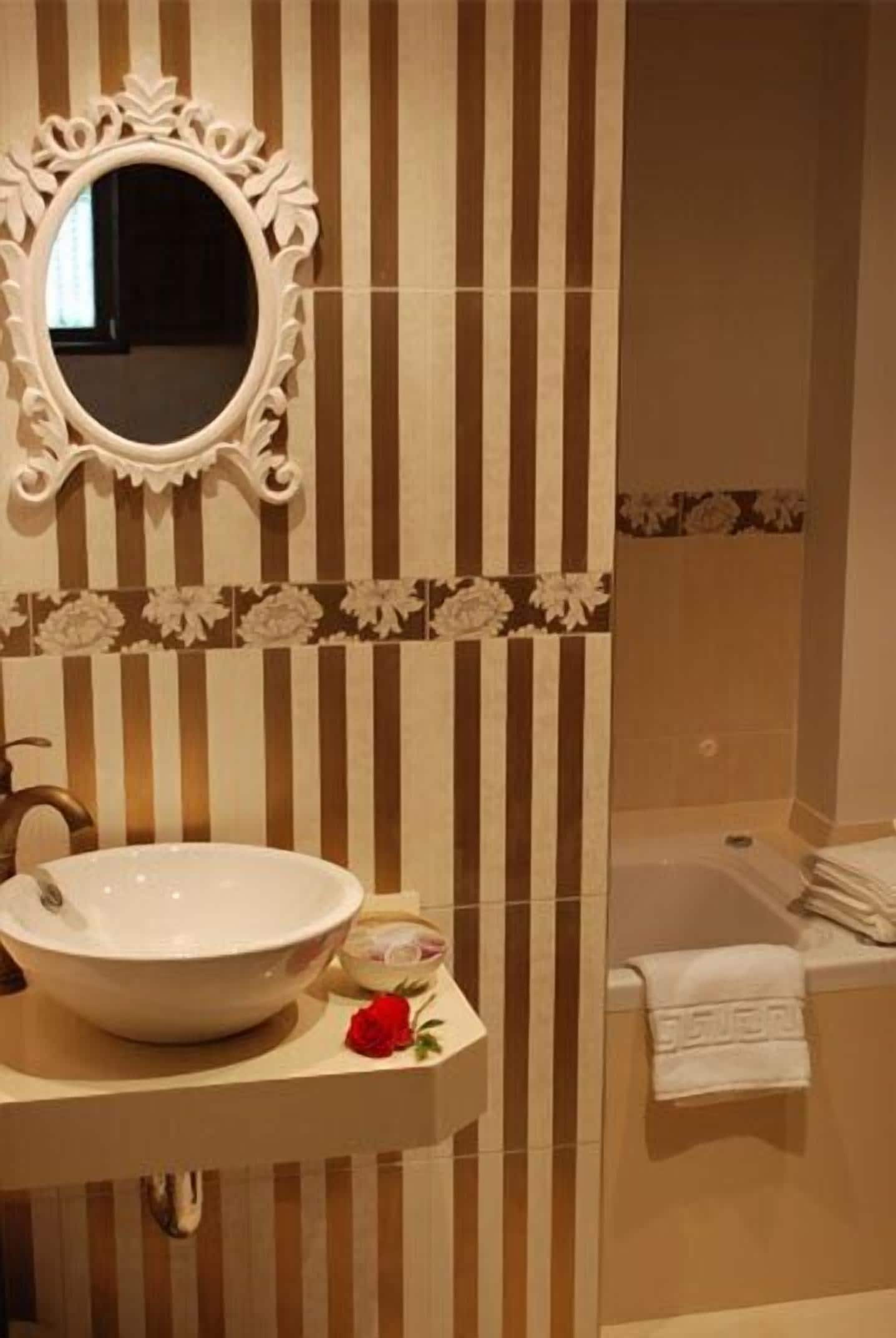 Ein Badezimmer mit einem großen, ovalen Spiegel, einem weißen Waschbecken und einer Badewanne.