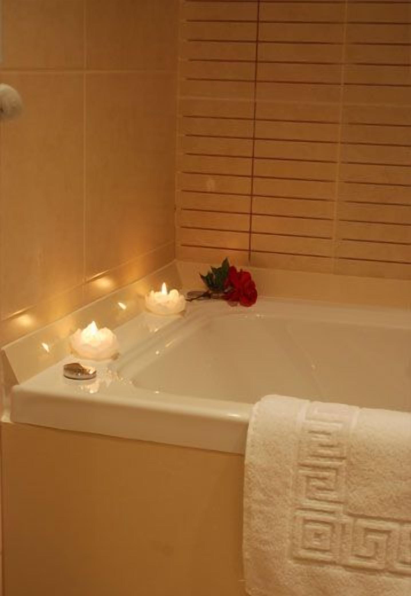 Eine Badewanne mit Kerzen und einer Rose.