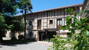 A stone building with a tiled roof and wooden balconies. - Posada La Corralada (Liérganes)