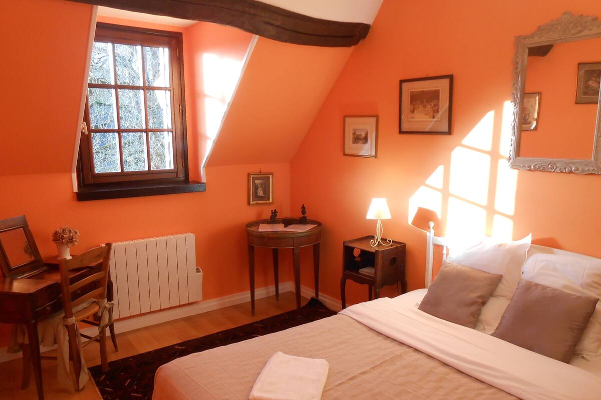 Un dormitorio con cama, escritorio, silla, ventana y radiador.