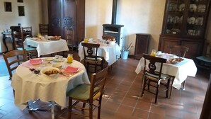 A dining area with round tables, chairs, and a chandelier. - B&B La Ferme Des Bordes (Pontlevoy)