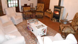 A cozy living room with white sofas, a patterned rug, a fireplace, and a chandelier. - B&B La Ferme Des Bordes (Pontlevoy)